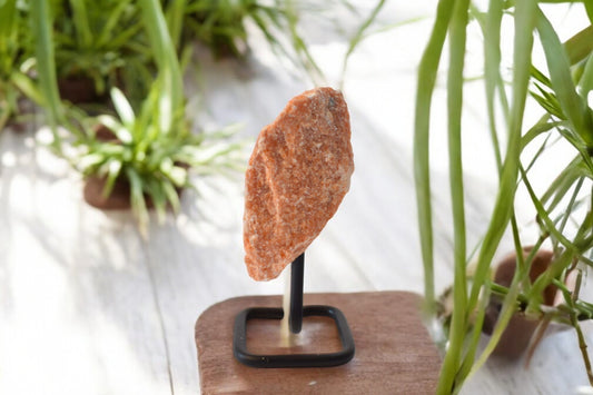 Ruw brok oranje calciet op metalen standaard